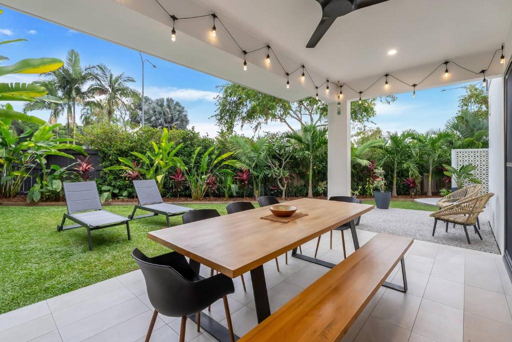 een eethoek in de openlucht met een houten tafel en stoelen bij Argentea Cove - Poolside Escape near Palm Cove Beach in Palm Beach