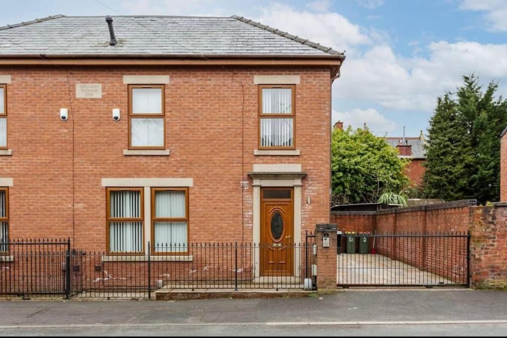 una casa de ladrillo con una puerta marrón y una valla en Albert Stays - 5 bed Sleeps 11 - Free Parking, en Preston