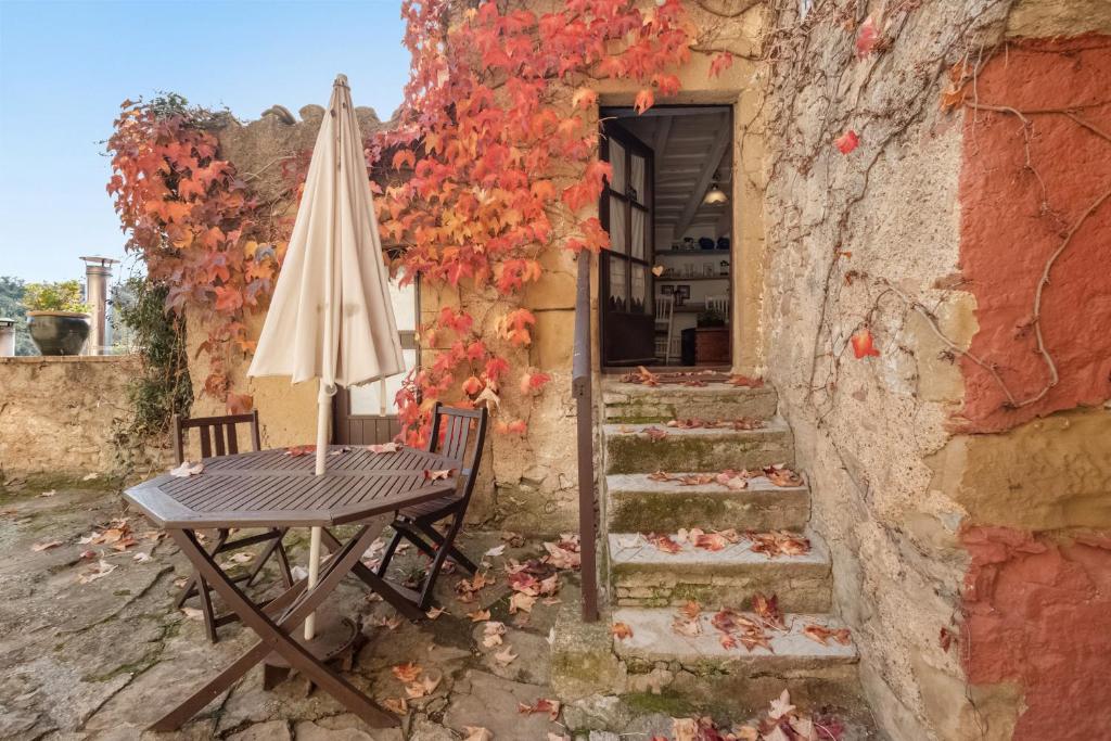 Una mesa y una sombrilla junto a un edificio de piedra. en Casa del Pastor-Brugarolas Village, en Castelltersol
