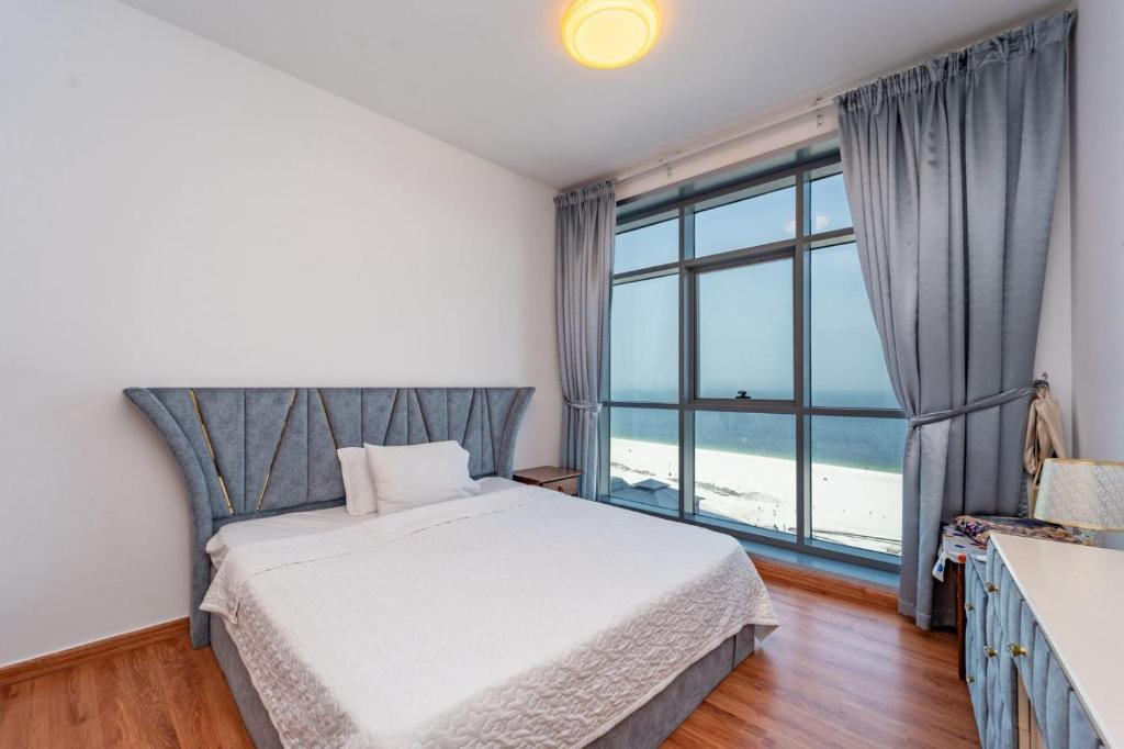 a bedroom with a bed and a large window at Sunset Beach View Holiday Homes in Ajman 