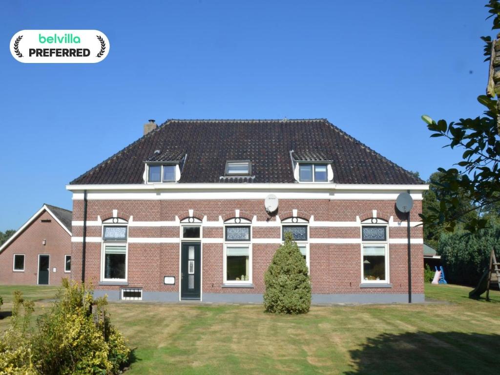een groot gebouw van rode baksteen met een zwart dak bij Farmhouse in Haarlo near Lake Hambroek in Haarlo
