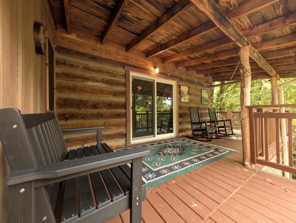 a porch of a log cabin with chairs and a table at The Elk's Apple Grove, Upper Suite, Real Log Cabin in Maggie Valley