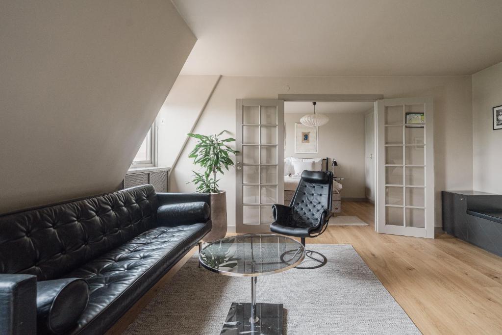 a living room with a black leather couch and a glass table at TwentySix in Malmö