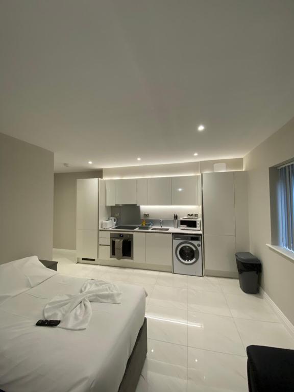 a white room with a bed and a kitchen at Cavendish Apartments in High Wycombe