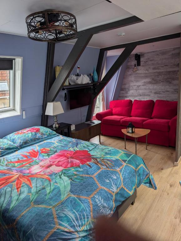 a bedroom with a bed and a red couch at Het Zwanenest in Harlingen