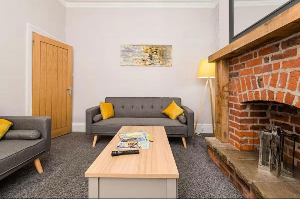 sala de estar con sofá y chimenea de ladrillo en Carnarvon Stays - 2 bed home, en Preston