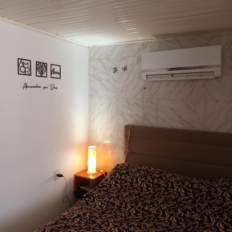 Un dormitorio con una cama y una lámpara en una mesita de noche. en Pousada da Maria Guapa, en São Gabriel