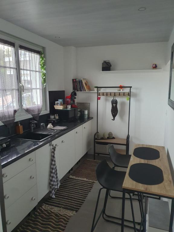 eine Küche mit weißen Schränken und einem Tisch und Stühlen in der Unterkunft Pleasant little cottage in Pont-sur-Yonne