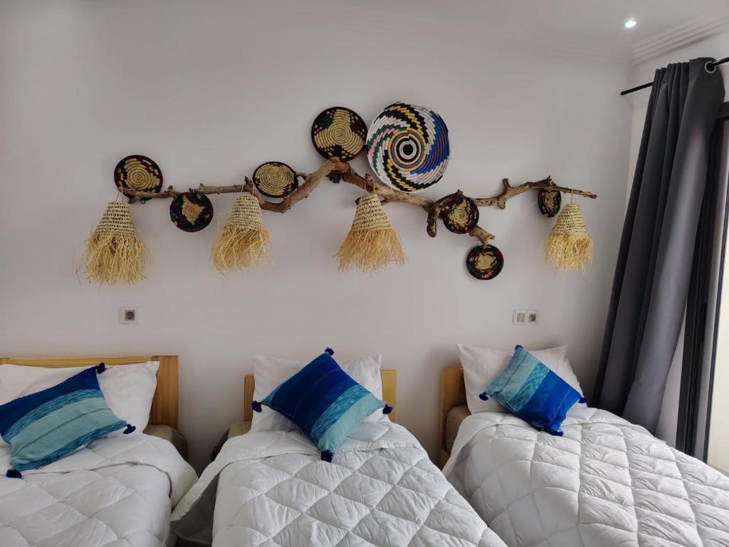a bedroom with two beds and hats on the wall at Mira bay surf house in Imsouane
