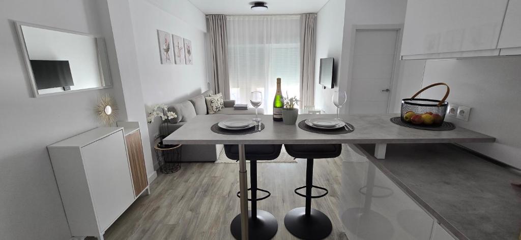 a kitchen with a table with plates and a bottle of wine at Apartamentos playa Romanilla in Roquetas de Mar