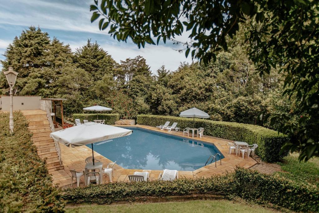 a pool with chairs and umbrellas in a yard at Roteiros Adorai in Piedade