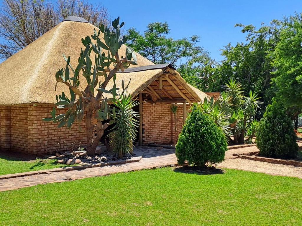 a small brick building with a thatch roof at Buck Hill Bush Lodge in Maanhaarrand