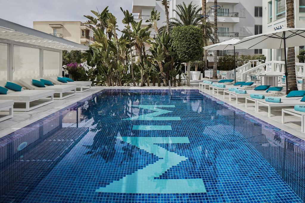 una gran piscina con sillas y sombrilla en MIM Ibiza Member of Melia Collection, en Ibiza