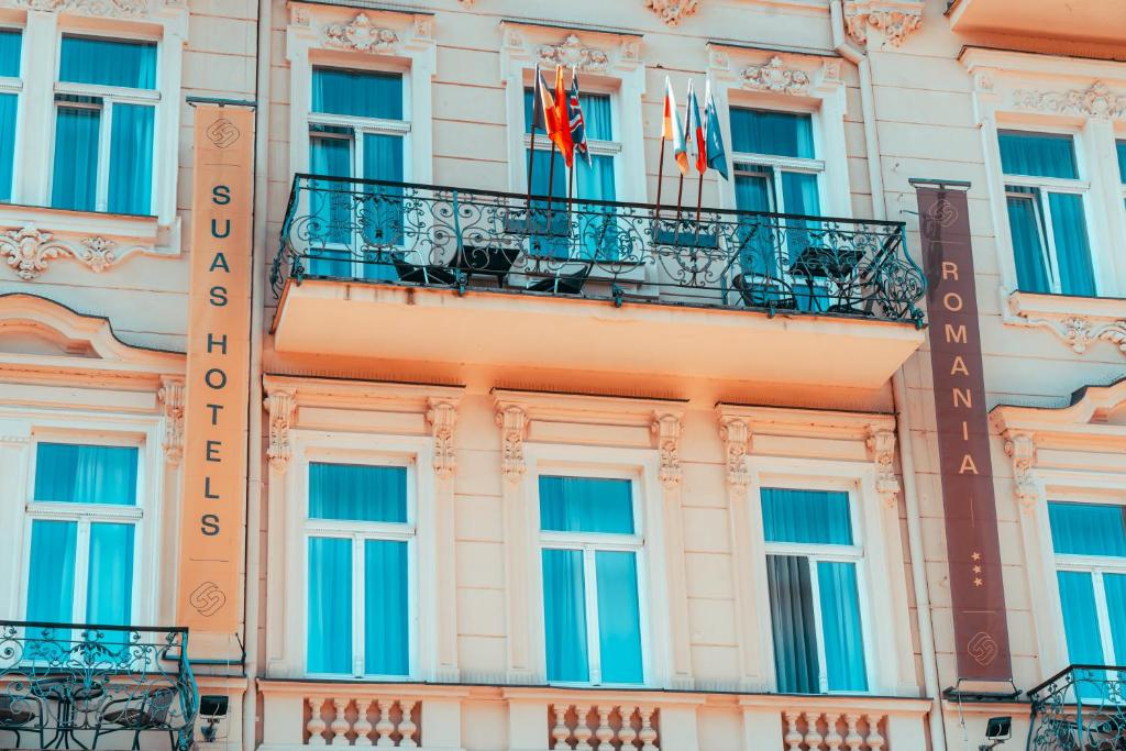 a building with a balcony and flags on it at Romania in Karlovy Vary