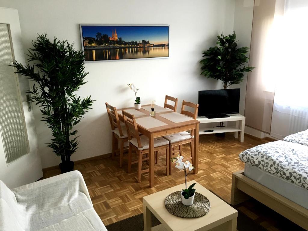 een woonkamer met een tafel en stoelen en een bed bij Arcaden Apartment in Regensburg