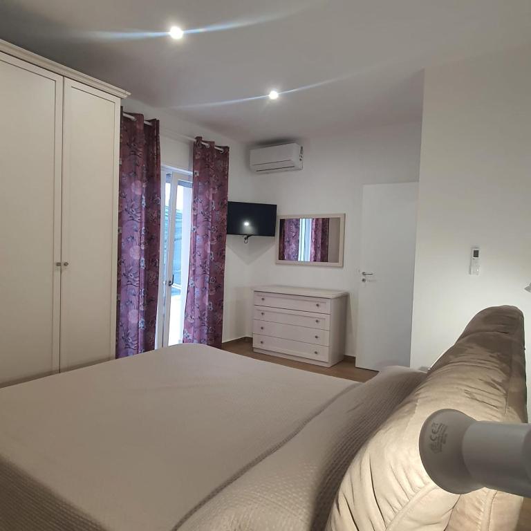 a white bedroom with a bed and a dresser at Villa MelVin in Stazione di Paestum