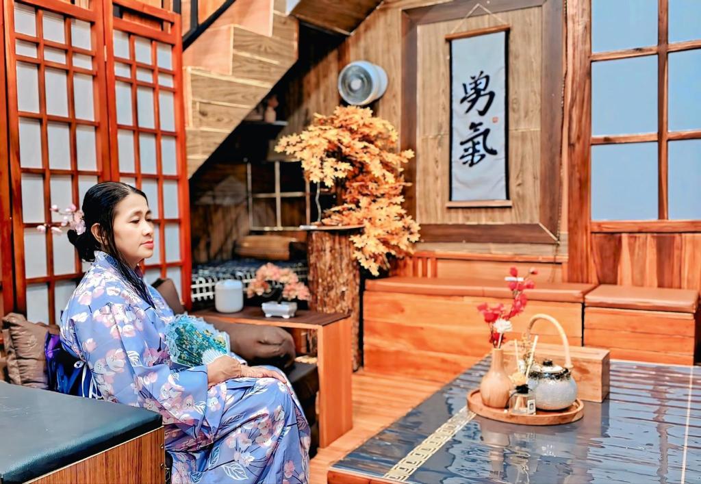 Eine Frau, die an einem Tisch in einem Zimmer sitzt. in der Unterkunft Hanki Guest House syariah in Gadok 1