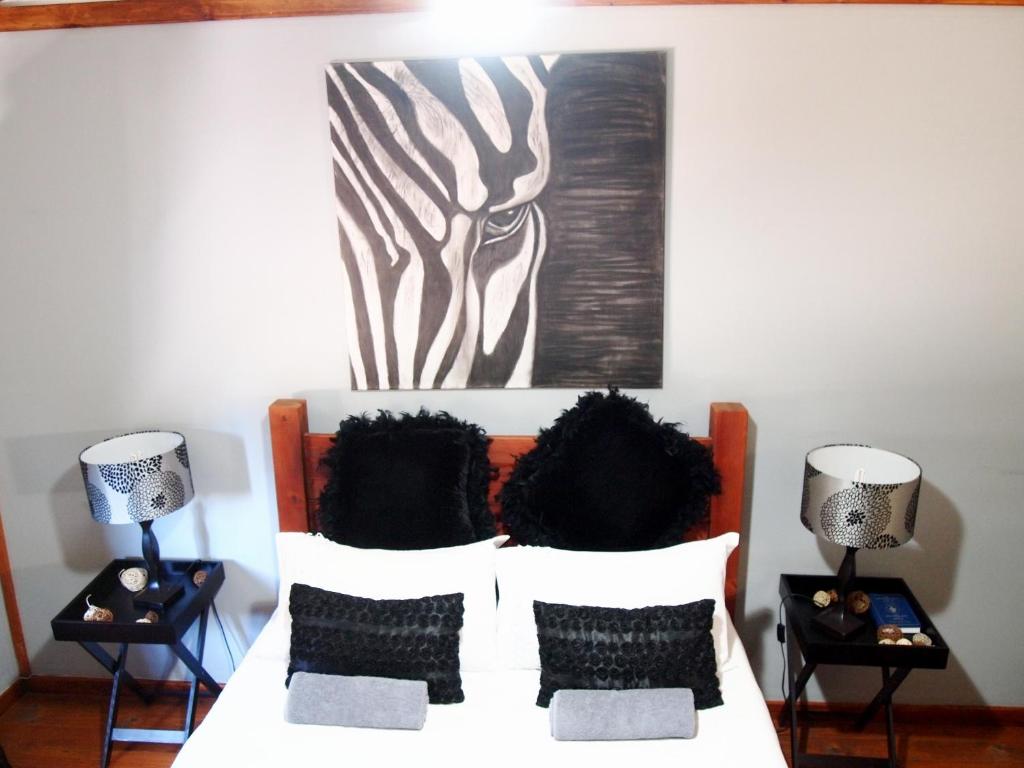 ein Schlafzimmer mit einem Bett mit zwei Lampen und einem Gemälde in der Unterkunft Havana Nights in Graskop