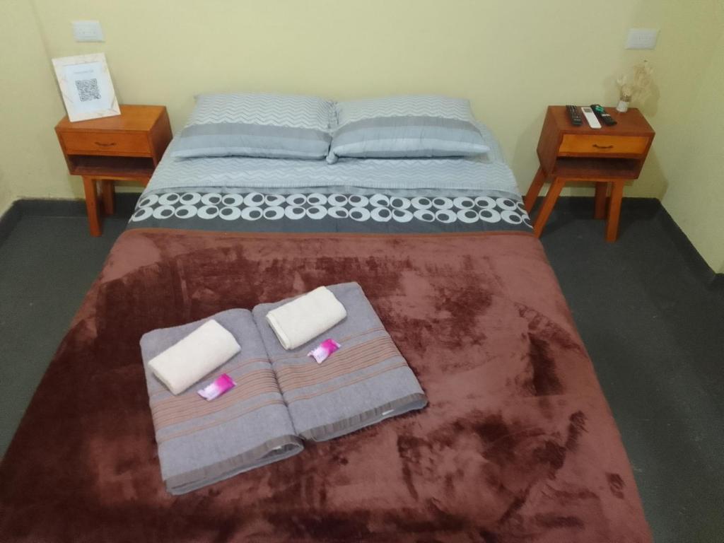 a bedroom with a bed with two towels and two tables at Departamento Monoambiente-Selva Stay Iguazu in Puerto Iguazú