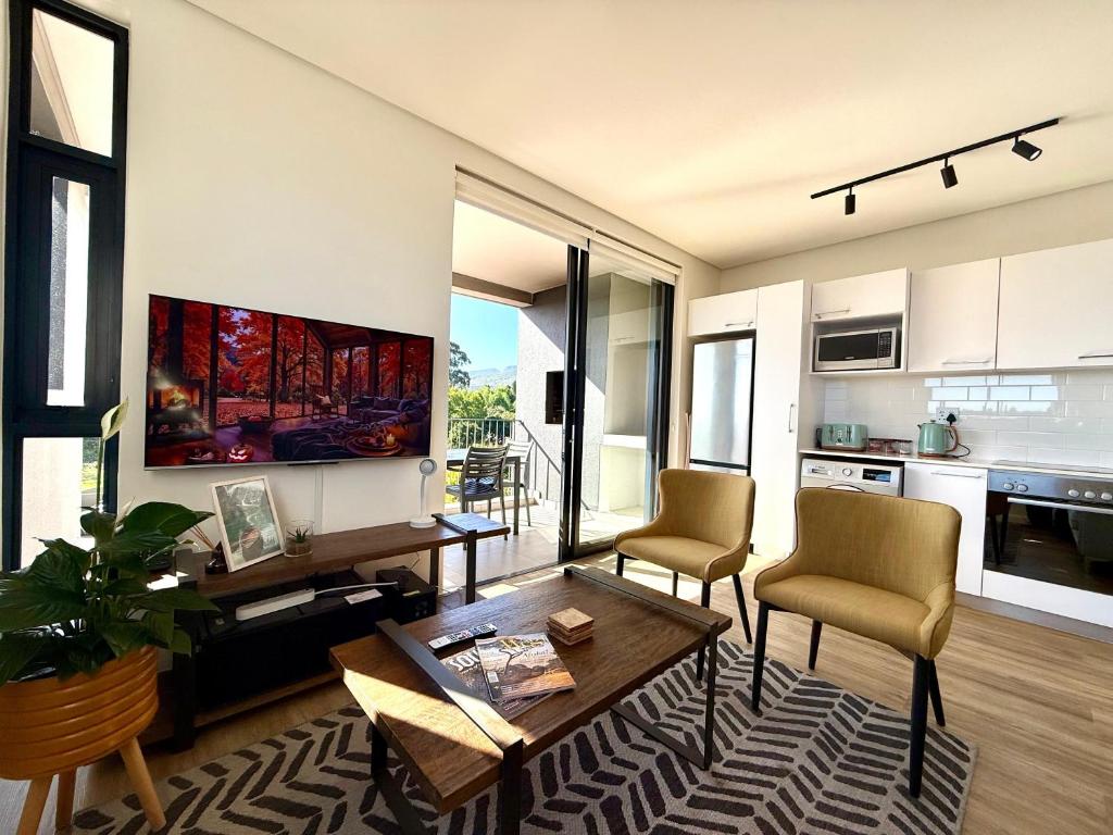 a living room with a table and chairs and a kitchen at Urban Escape - Le Jardin Unit 301 in George