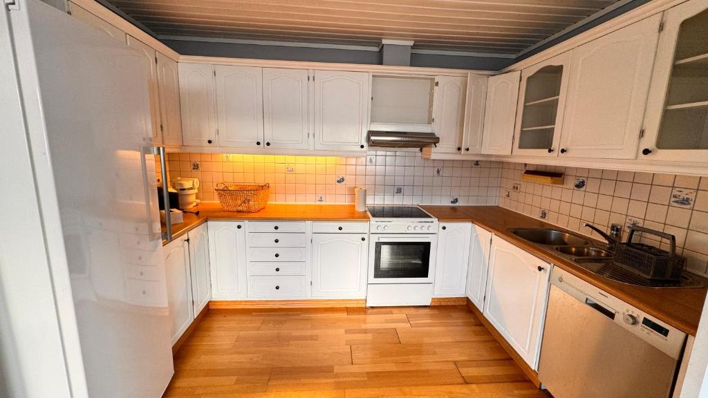 a kitchen with white cabinets and a wooden floor at Rørvikjordet 12 flott hus ved utsikt in Drammen