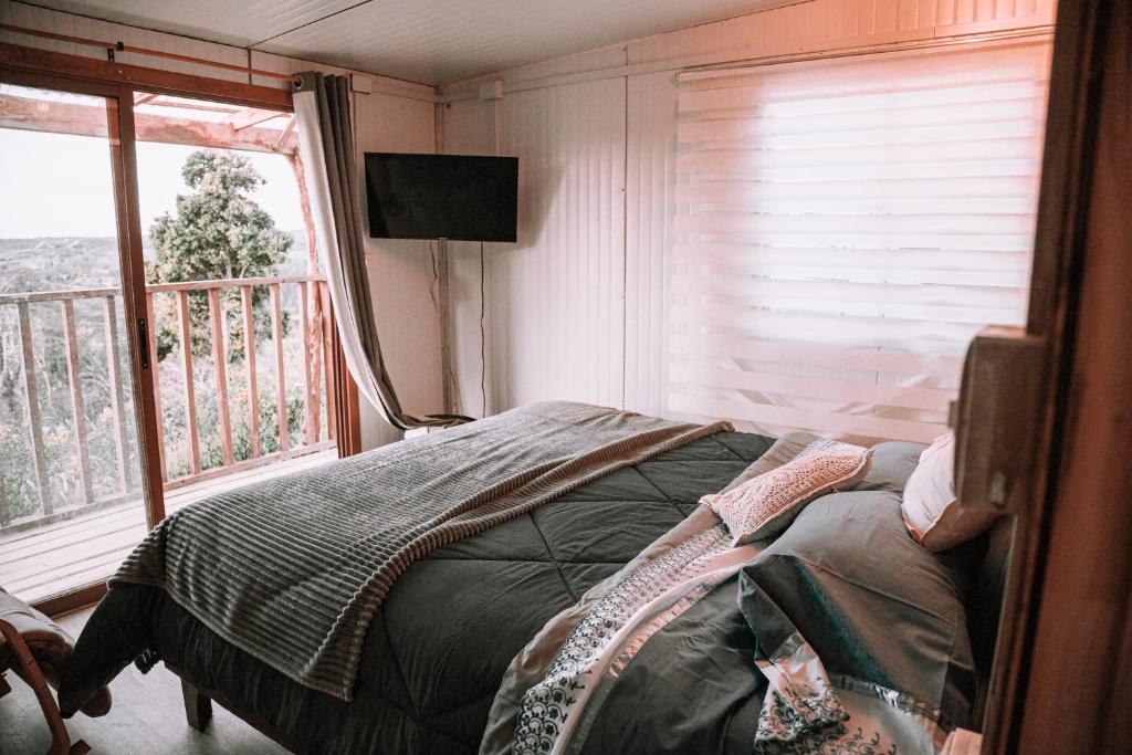 a bedroom with a bed and a large window at Dollinco Lodge in El Cerrillo