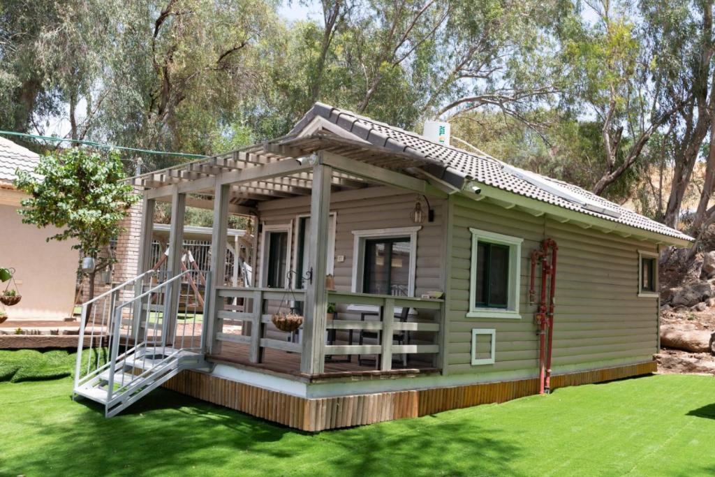 a small green tiny house with a porch at Pnina Yafa BaGalil Zimmer in Qiryat Shemona