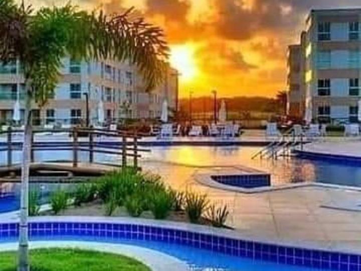 einen Pool mit einer Palme und einem Gebäude in der Unterkunft Porto de galinhas flats muro alto in Ipojuca