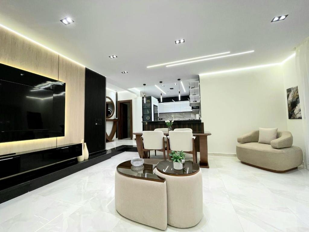 ein Wohnzimmer mit einem TV, einem Sofa und Stühlen in der Unterkunft Brand New Apartment Obour City in Obour