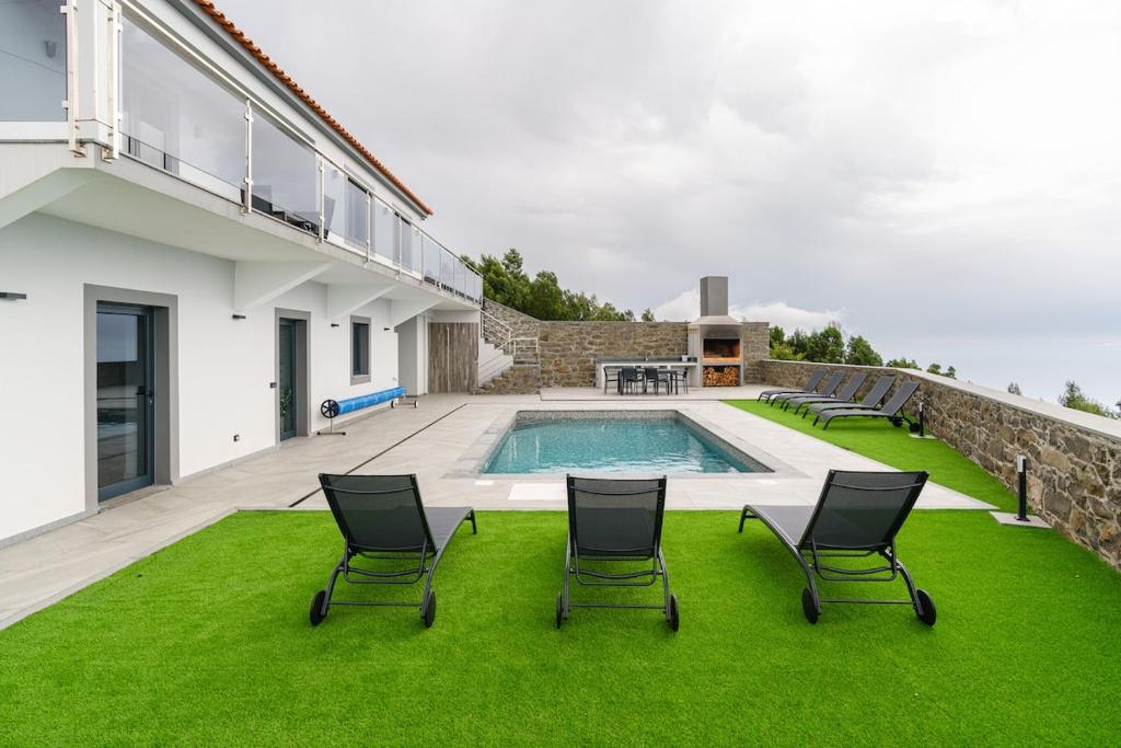 a house with a swimming pool and chairs on a lawn at Sunny Side II Free heated pool in Tábua
