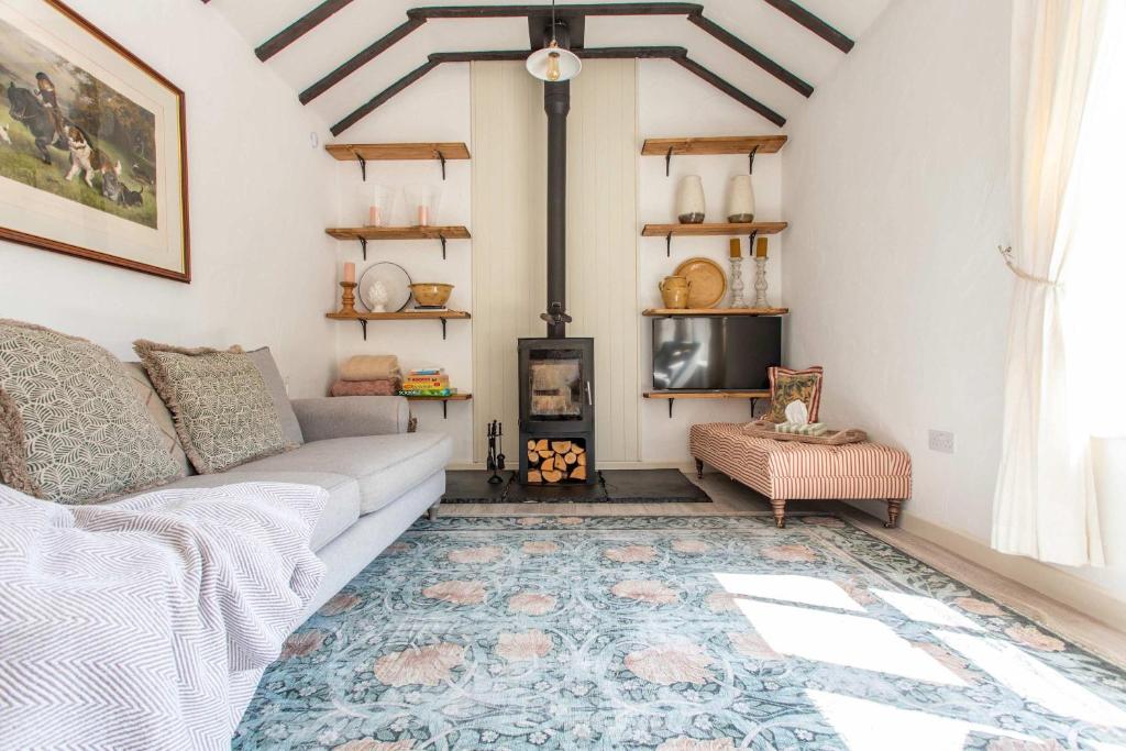 WoolvertonにあるThe Cowshed - Country Retreatのソファと暖炉のあるリビングルーム