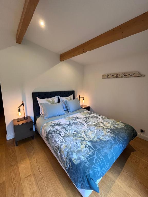 a bedroom with a bed with blue sheets and two lamps at Le P’tit Bois Doré in Blanquefort