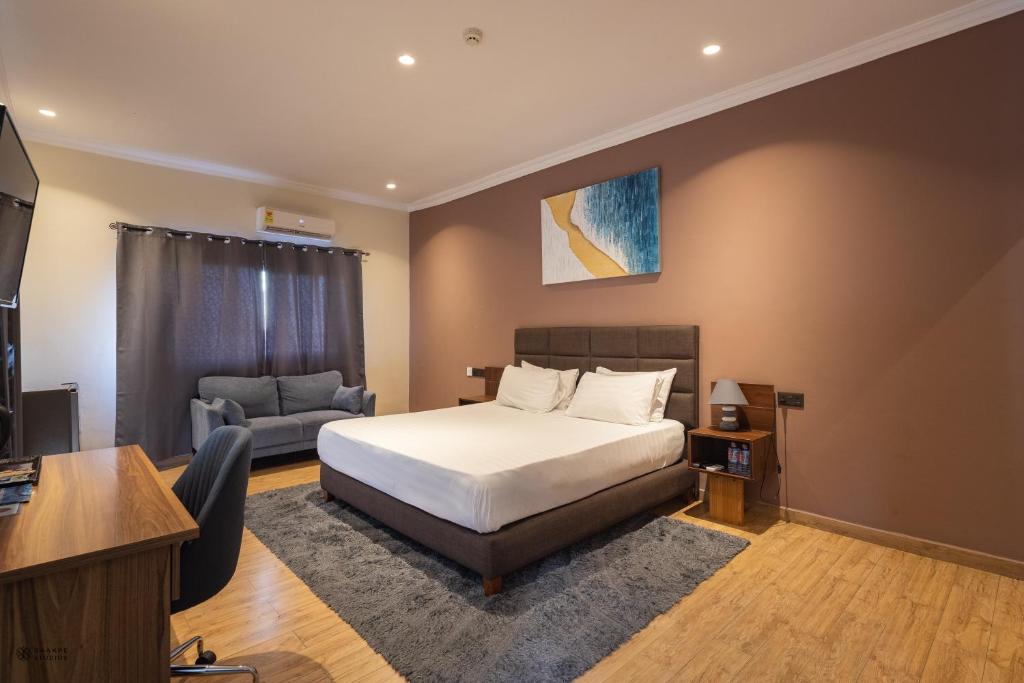 een slaapkamer met een bed, een bureau en een bank bij Nouveau Hotel in Accra