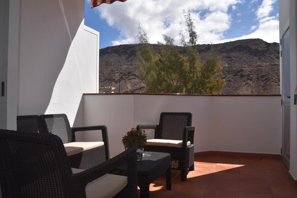 a patio with chairs and a view of a mountain at Vv Faro in Puerto de Mogán