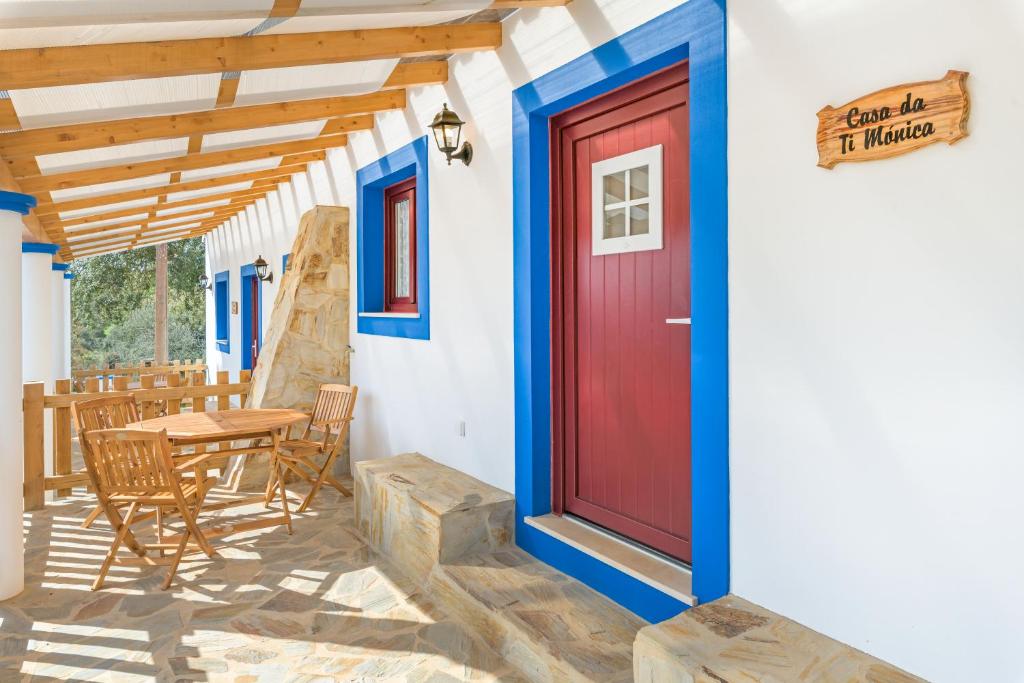 una puerta roja en una casa con mesa y sillas en Casa da Ti Mónica, en Zambujeiras