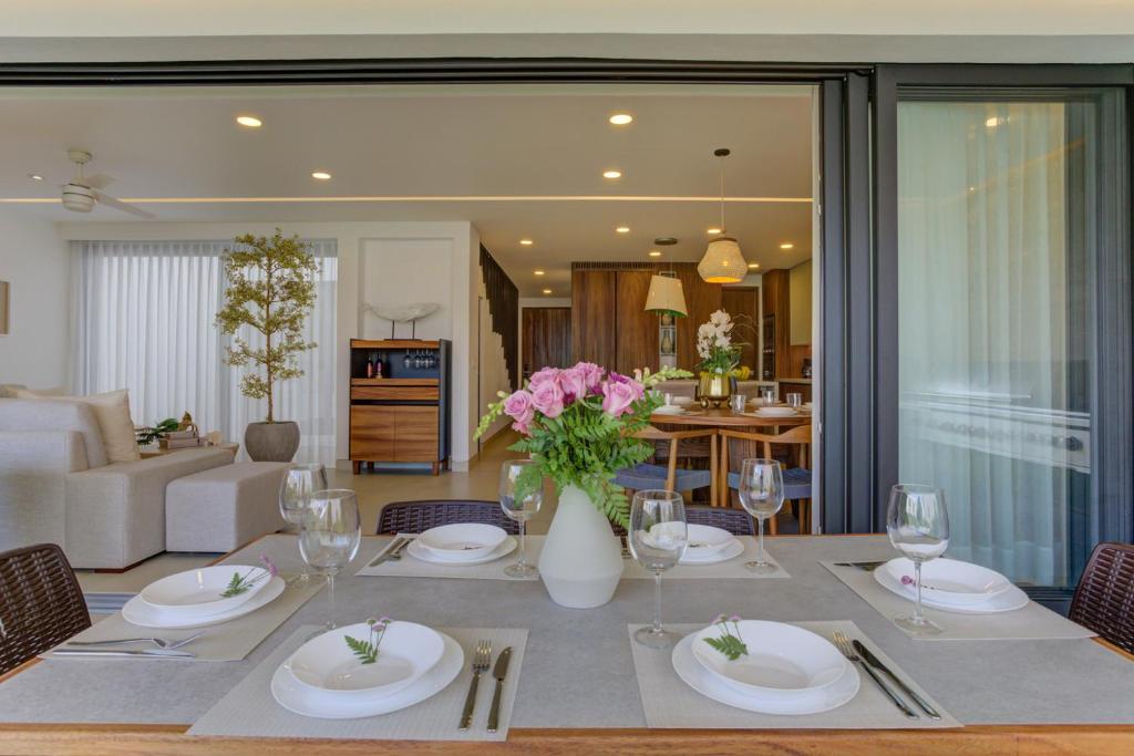 a dining room with a table with plates and wine glasses at Vista Natura, Luxury Home Near the Beach in Nuevo Vallarta 