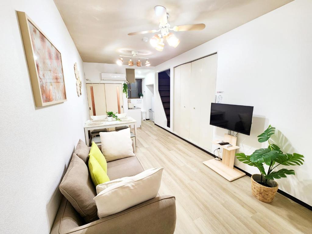 a living room with a couch and a tv at D,A-House OSAKA in Osaka