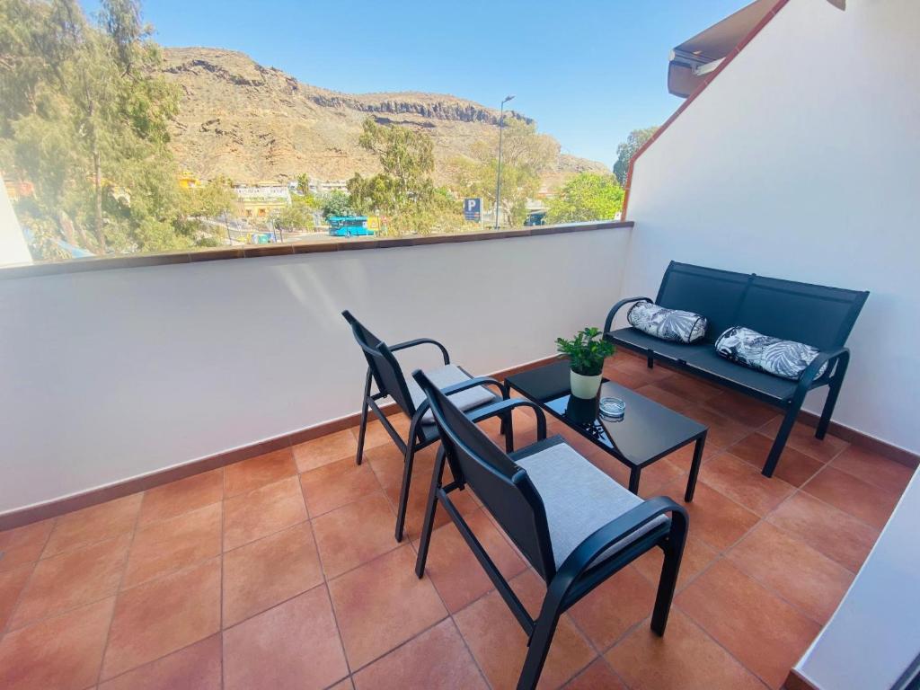 a balcony with chairs and a table and a window at Vv Estrella in Puerto de Mogán