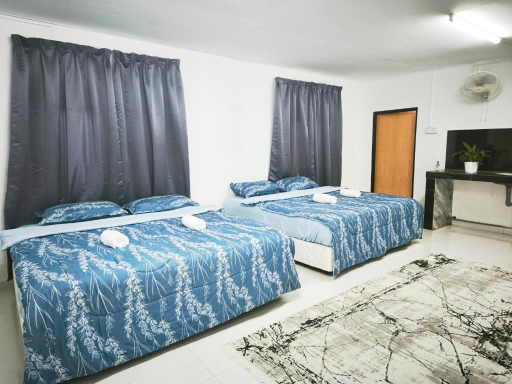 a bedroom with two beds with blue comforters at OYO 91244 Aufa Chalet in Kuala Terengganu