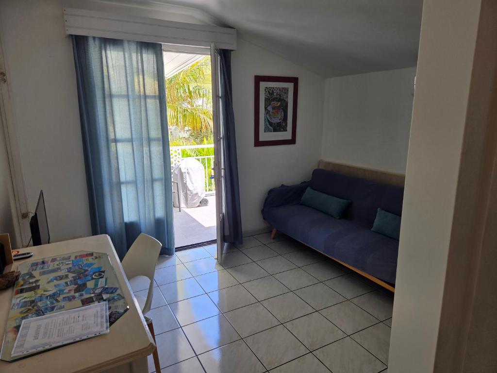 a living room with a blue couch and a table at Appart Cocotiers in La Saline les Bains