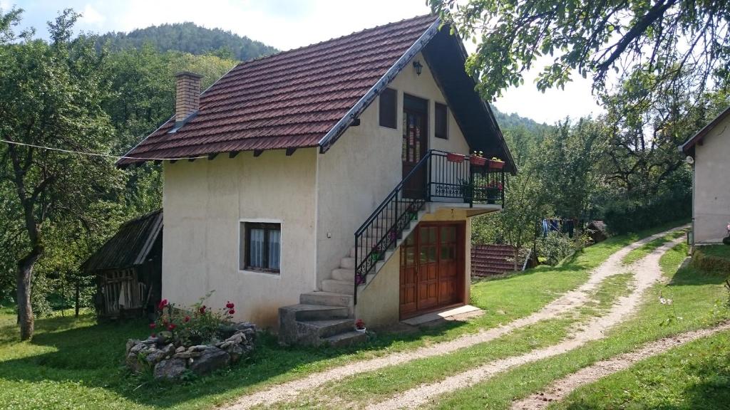 una piccola casa bianca con una scala accanto a una strada sterrata di Apartman Ana a Mokra Gora