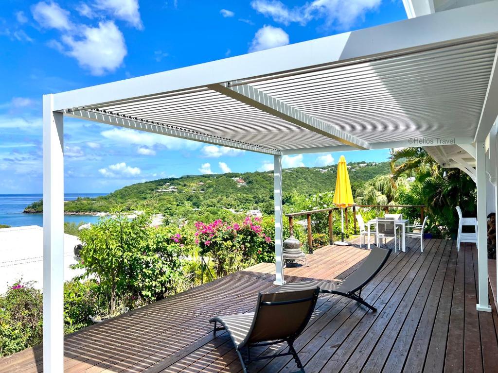 a white pergola on a deck with chairs and tables at Villa Tramontane. Vue mer. 2 chambres. Ferry Deshaies. in Deshaies