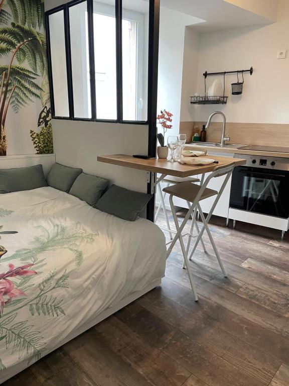 a bedroom with a bed and a table and a kitchen at CLIMATISÉ appartement design hypercentre Gare & espresso offert in Castelnaudary