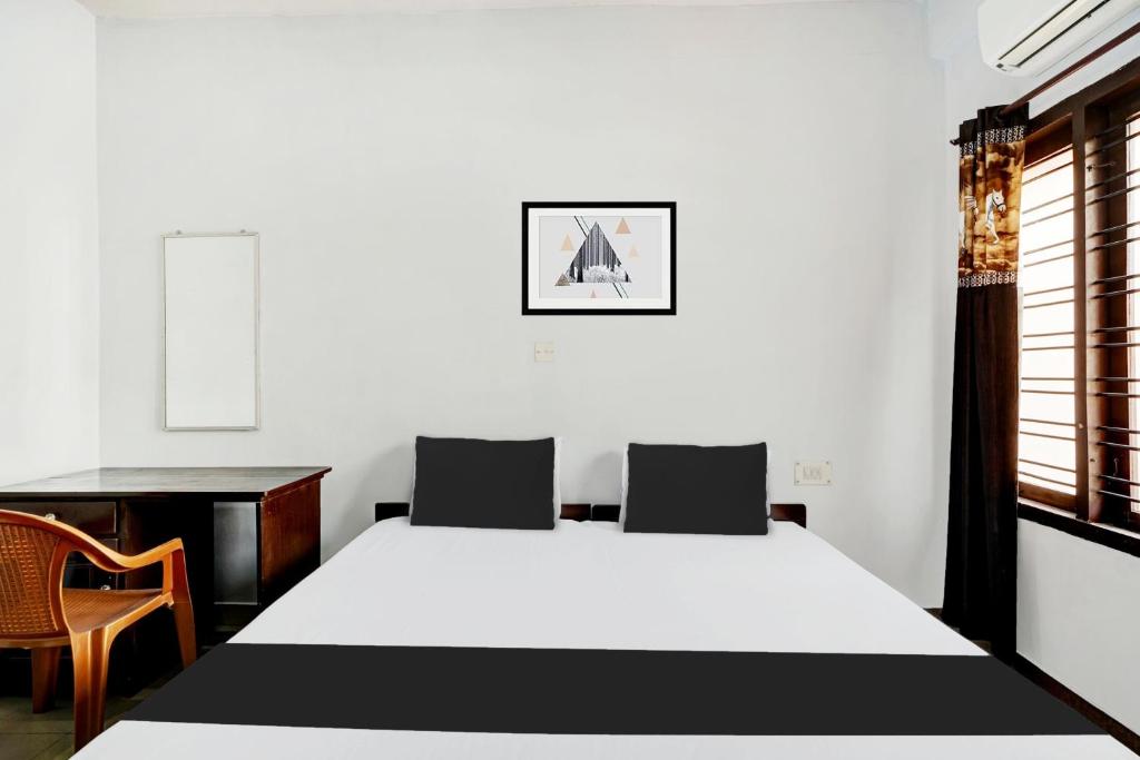 a bedroom with a bed and a desk and a chair at Hotel O THE HOME SPOT in Trivandrum