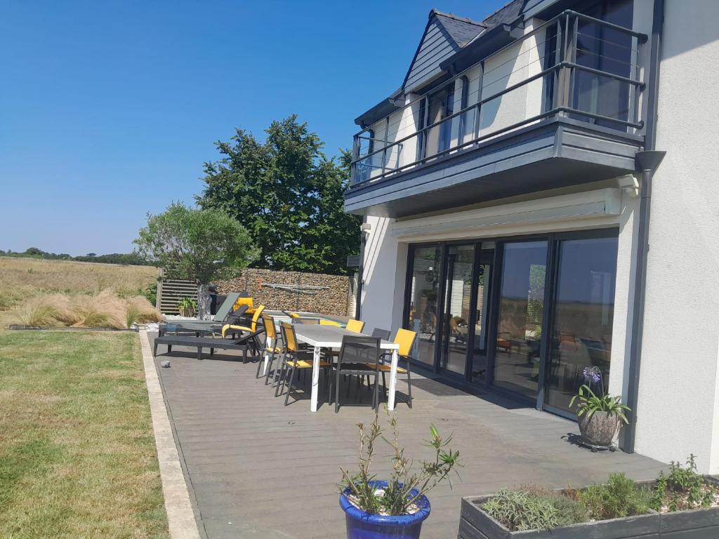 a deck with chairs and tables on a house at La maison du bonheur in Riantec
