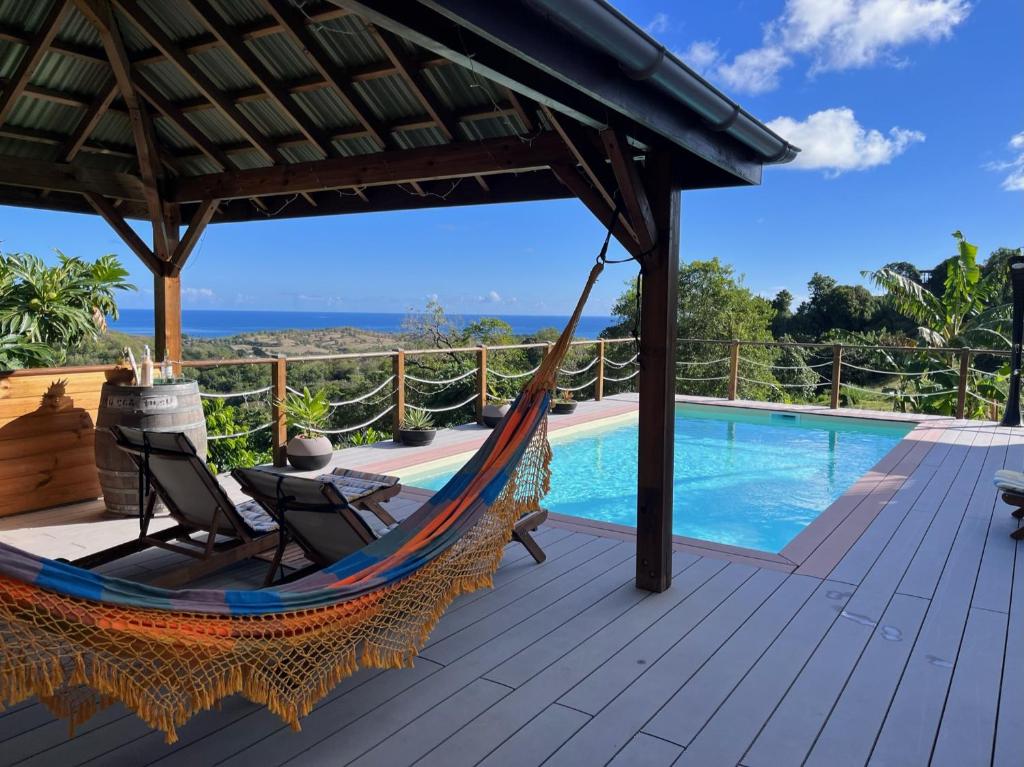 a hammock on a deck next to a swimming pool at La Maison d'Abigaelle in Le François