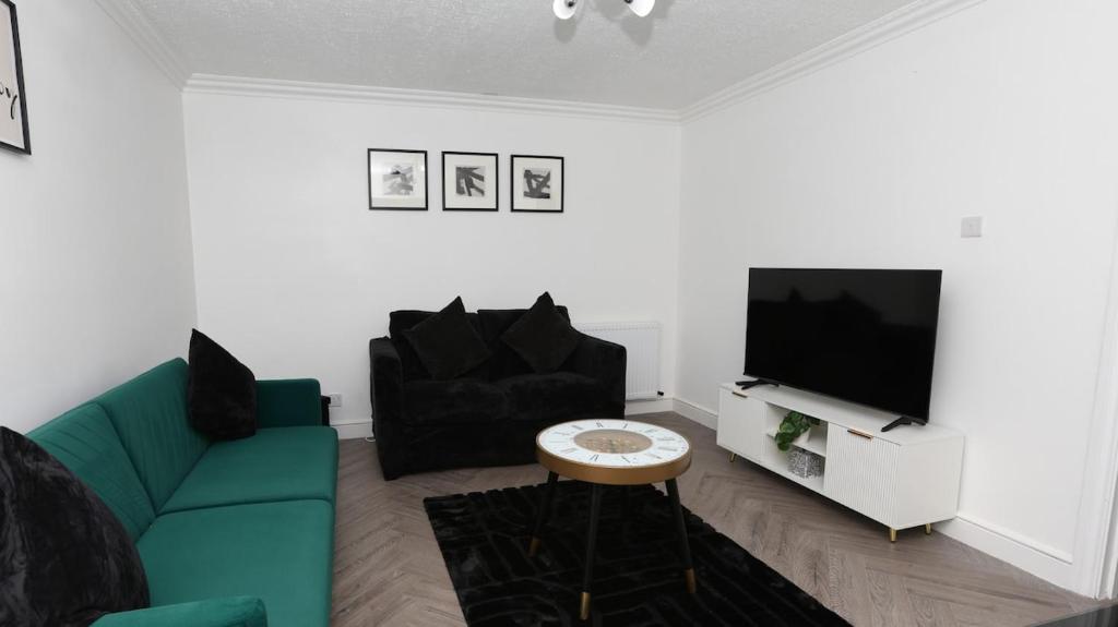 Una sala de estar con un sofá verde y un televisor. en Modern 3 bed house in Edmonton with private driveway parking, en Edmonton