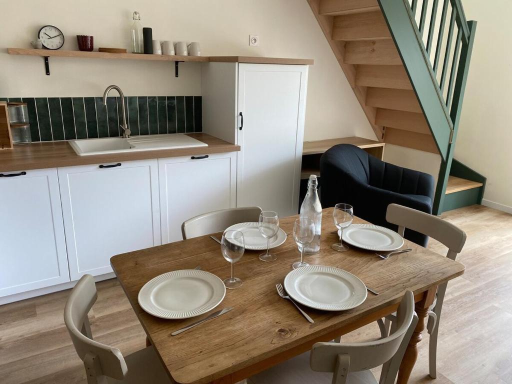 a wooden table with plates and wine glasses on it at Charming House in Beauvais in Beauvais
