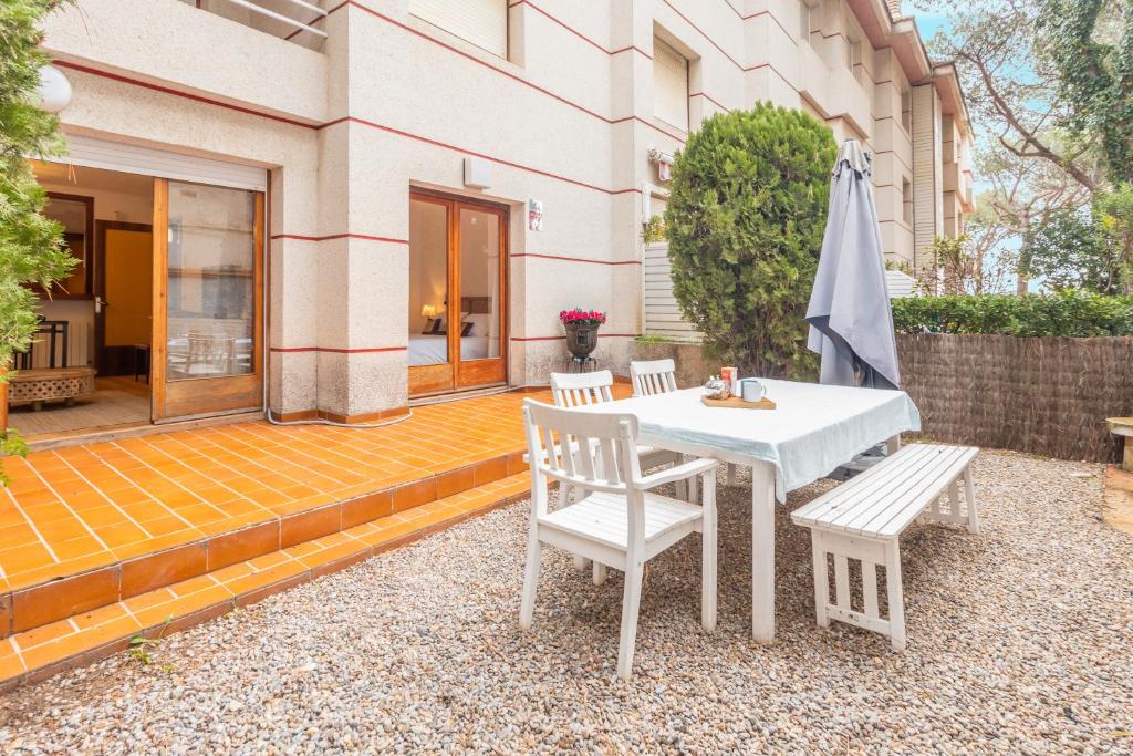 a patio with a white table and chairs and an umbrella at Apartamento con Jardin y Parking in Platja  d'Aro