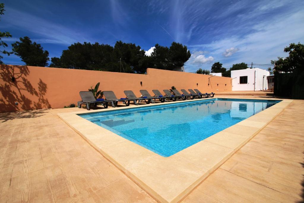 a swimming pool with chairs next to a wall at Villa Beso in San Antonio